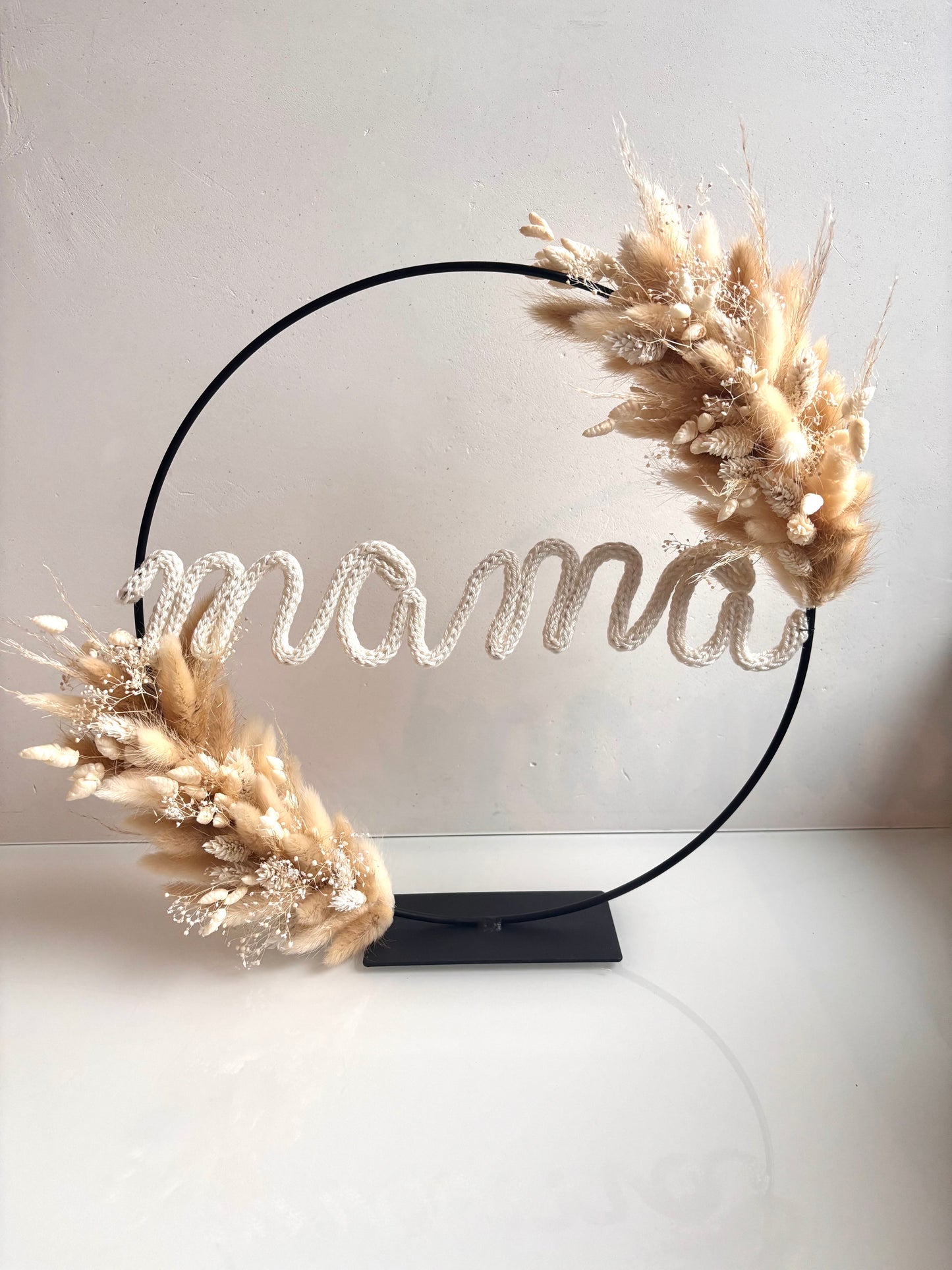OK - Metalen zwarte ring met langs 2 kanten droogbloemen
witte en beige droogbloemen
punnik in wit met naam mama
Diameter 30cm
Prijs: €45,00
Voorraad: 1