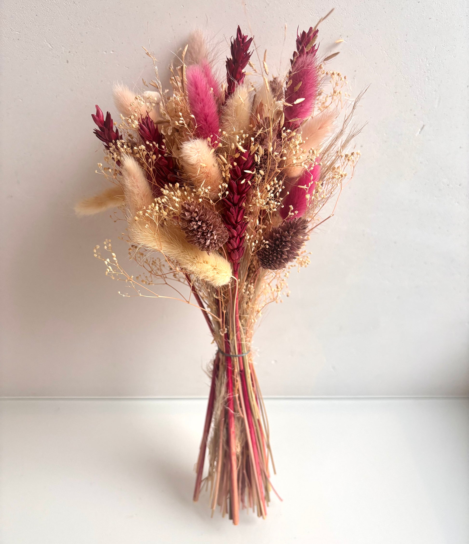 OK - Droogbloemen boeketTotale lengte boeket: 32cmPrijs: €19,90Voorraad: 1 Kleuren: wit, fuschia, oudroze, lichtroze. Soorten: lagurus, tarwe, phalaris, details sprieten beige