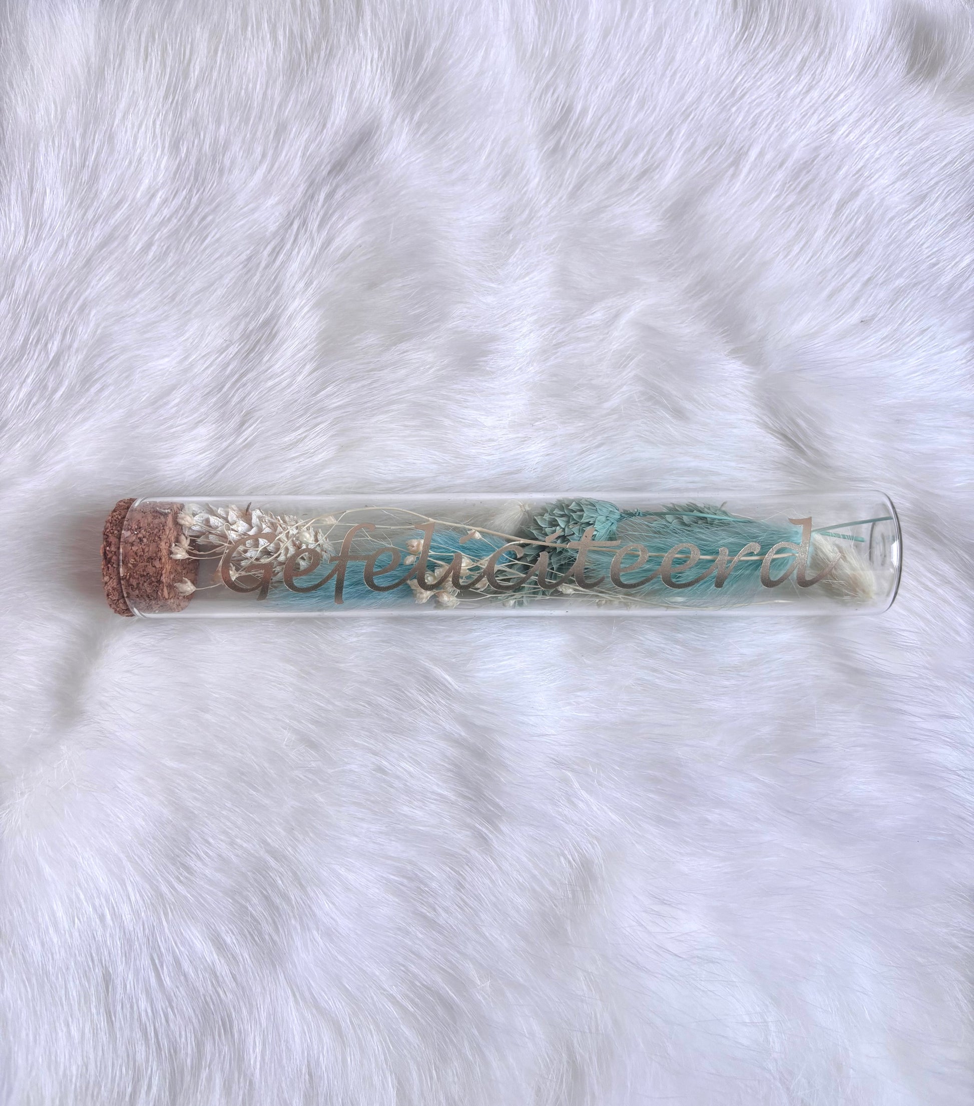 OK - Glazen buisje met kurk
Lichtblauw en witte droogbloemen
Tekst: gefeliciteerd goud
B 15cm 
D 2,5cm
Prijs: €6,50
Voorraad: 1