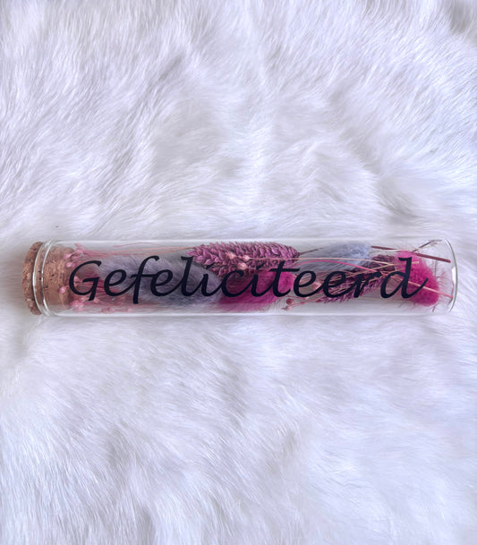 OK - Glazen buisje met kurk
Fuchsia en paarse droogbloemen
Tekst: gefeliciteerd zwart
B 15cm 
D 3cm
Prijs: €6,50
Voorraad: 1