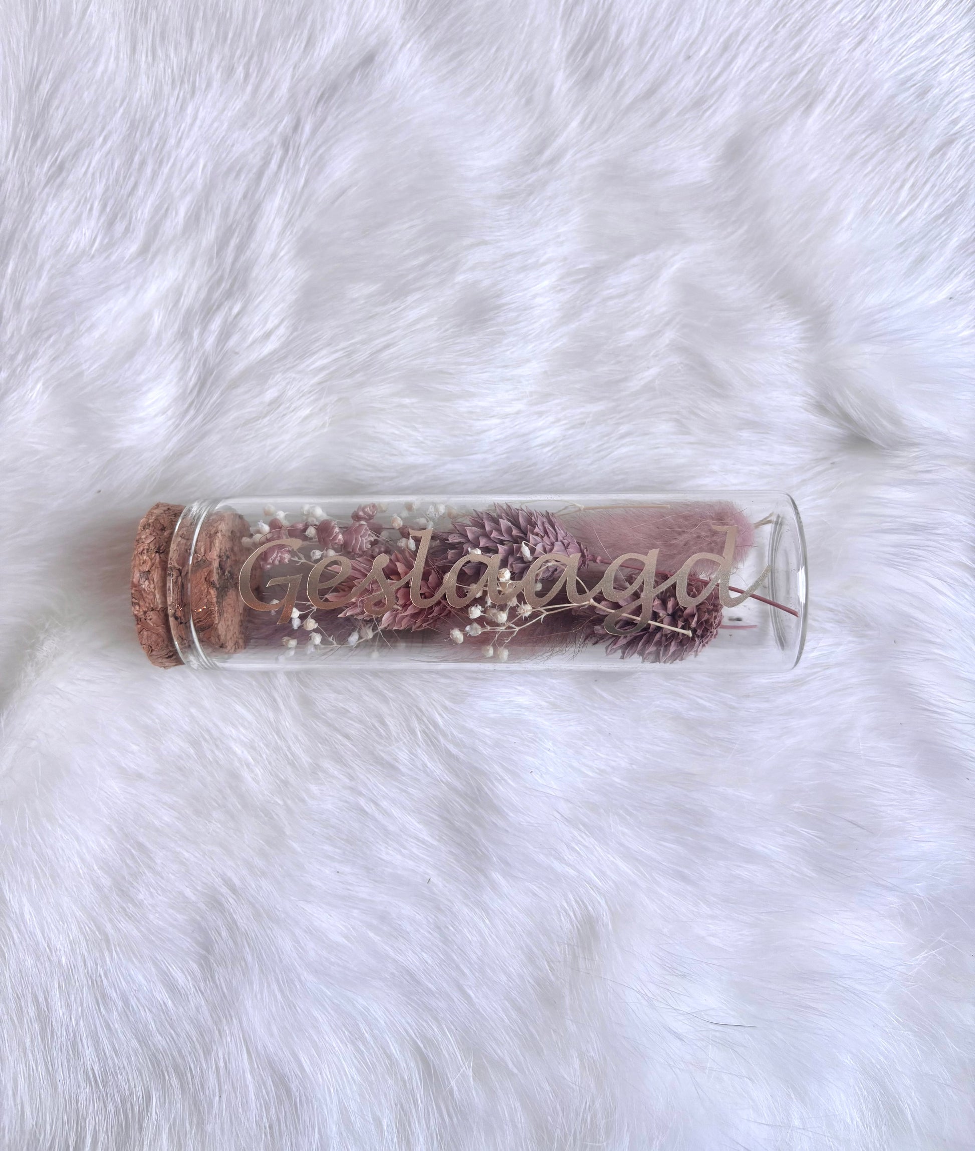 OK - Glazen buisje met kurk
oudroze en witte droogbloemen
Tekst: geslaagd goud
B 10cm 
D 3cm
Prijs: €5,50
Voorraad: 1